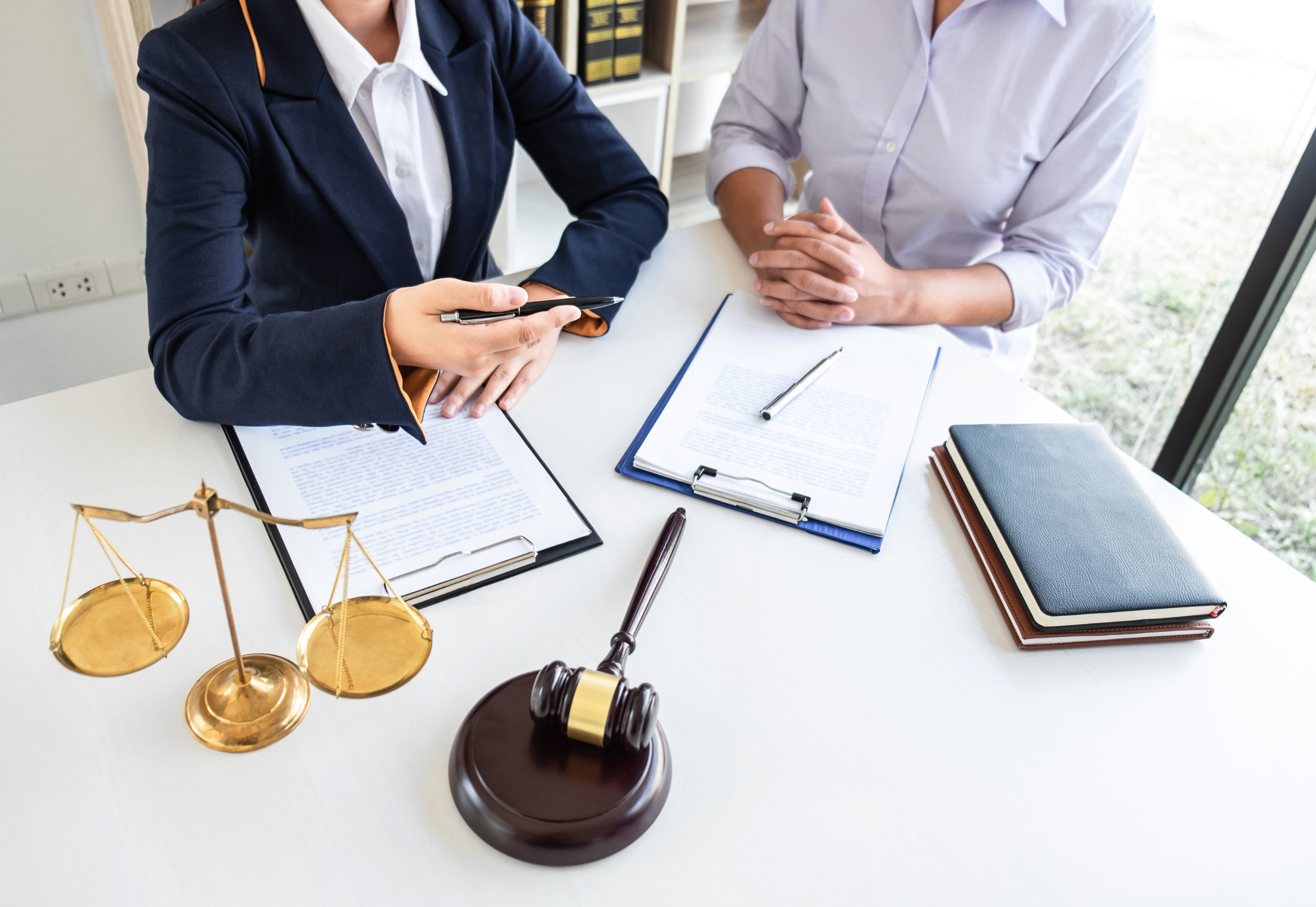Manos revisando documentos de una herencia junto a un testamento y llaves sobre la mesa.
