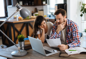 Persona trabajando en ordenador con una factura digital en pantalla y una calculadora sobre la mesa.